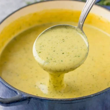 Bowl of creamy zucchini soup garnished with herbs and a drizzle of olive oil.