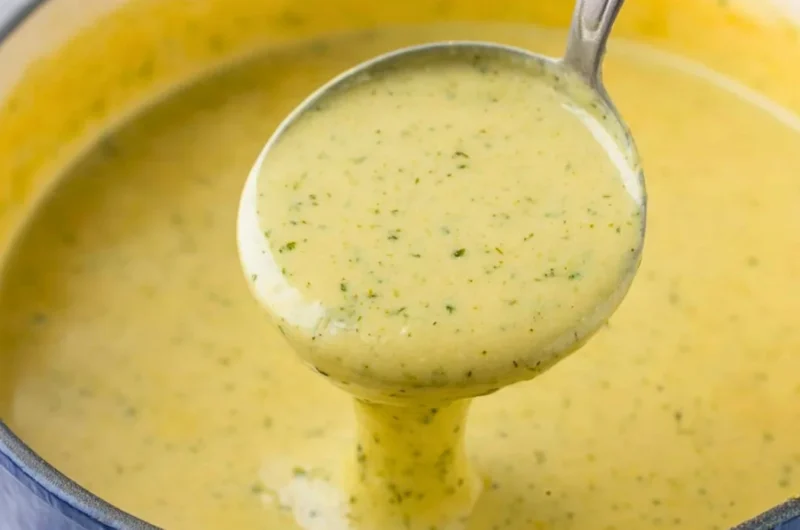 Bowl of creamy zucchini soup garnished with herbs and a drizzle of olive oil.