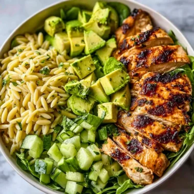 A colorful bowl of Grilled Chicken Orzo Salad with fresh vegetables.