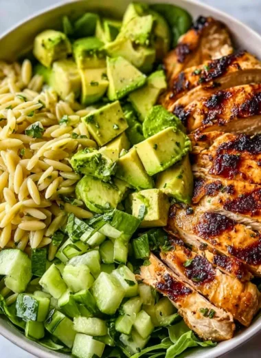 A colorful bowl of Grilled Chicken Orzo Salad with fresh vegetables.