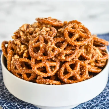 Bowl of colorful homemade snack mix with nuts, pretzels, and dried fruits.