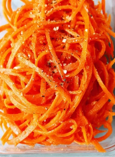 Colorful raw carrot salad with fresh ingredients and dressing