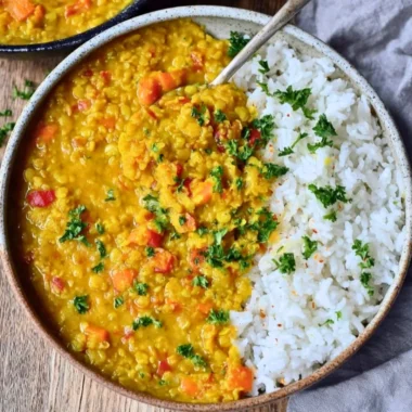 Bowl of vegan red lentil dahl with spices and herbs