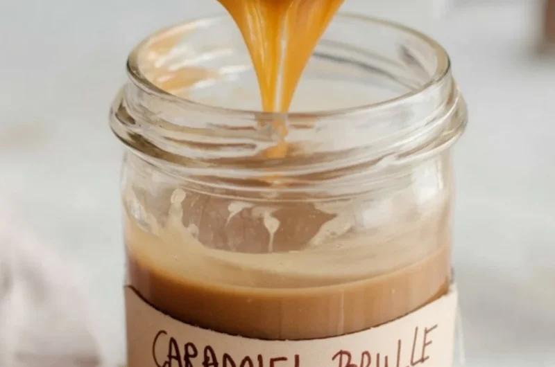 Caramel Brulee Latte Syrup in a glass with coffee and caramel drizzle