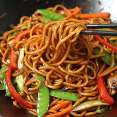 Delicious bowl of Lo Mein noodles topped with vegetables and sauce.