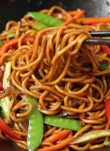 Delicious bowl of Lo Mein noodles topped with vegetables and sauce.