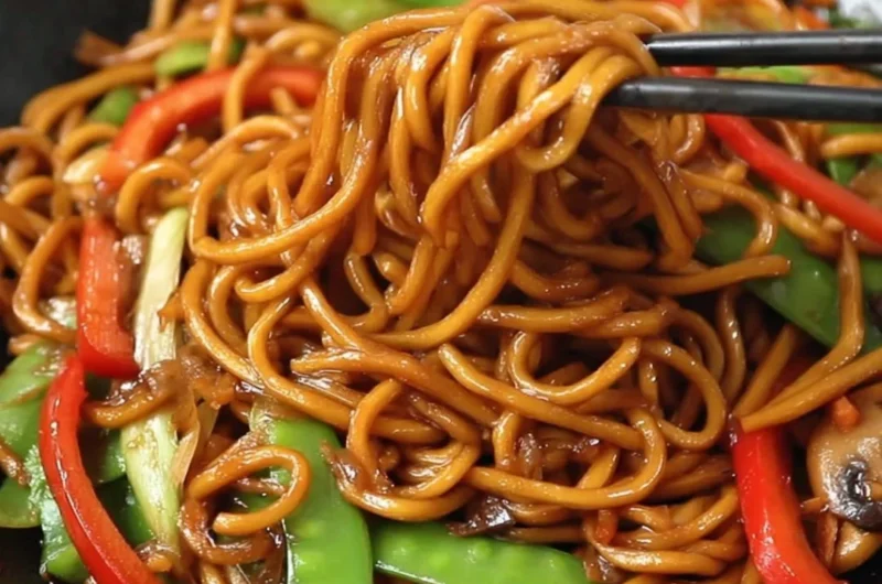 Delicious bowl of Lo Mein noodles topped with vegetables and sauce.