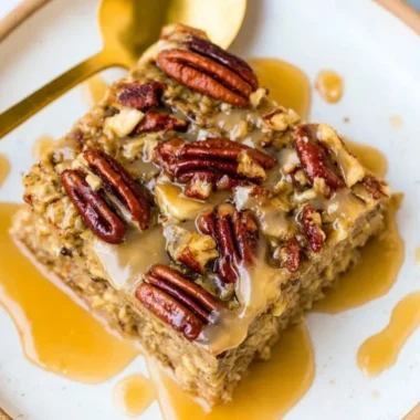 Maple Pecan Baked Oatmeal topped with nuts and syrup in a baking dish
