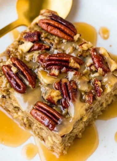 Maple Pecan Baked Oatmeal topped with nuts and syrup in a baking dish