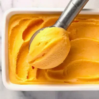Delicious peach sorbet served in a chilled bowl with fresh peach slices
