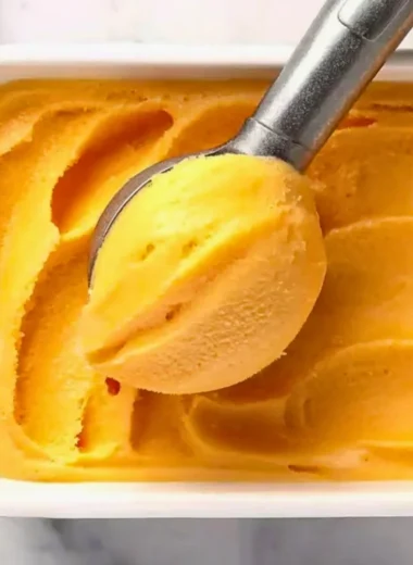 Delicious peach sorbet served in a chilled bowl with fresh peach slices