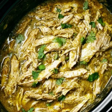 Delicious Salsa Verde Chicken cooked in a crockpot, garnished with fresh herbs.