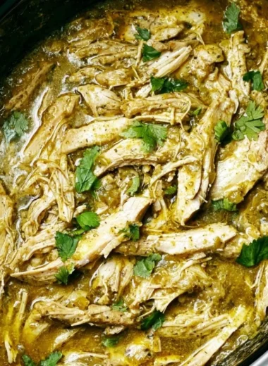 Delicious Salsa Verde Chicken cooked in a crockpot, garnished with fresh herbs.
