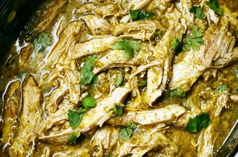 Delicious Salsa Verde Chicken cooked in a crockpot, garnished with fresh herbs.