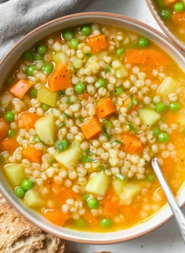 Bowl of hearty homemade barley soup with vegetables and herbs