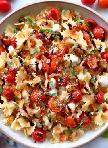 Colorful Bruschetta Pasta Salad garnished with fresh basil and tomatoes.