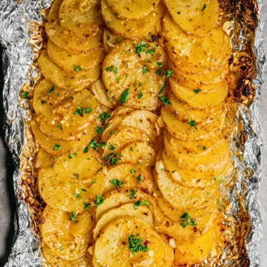 Grilled potatoes in foil packets on a barbecue grill.