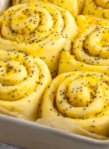 Freshly baked lemon rolls with icing on a rustic wooden table