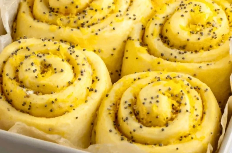 Freshly baked lemon rolls with icing on a rustic wooden table