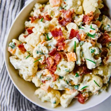A colorful loaded cauliflower salad with fresh vegetables and toppings.