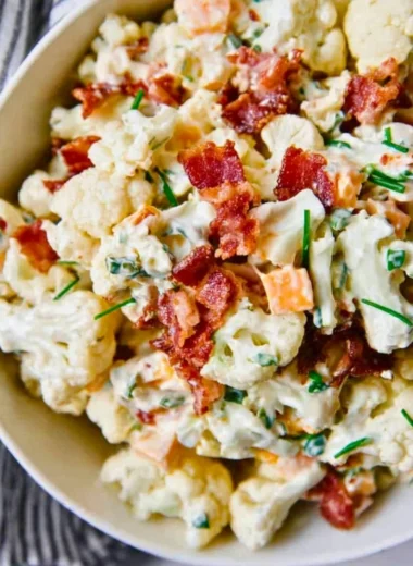 A colorful loaded cauliflower salad with fresh vegetables and toppings.