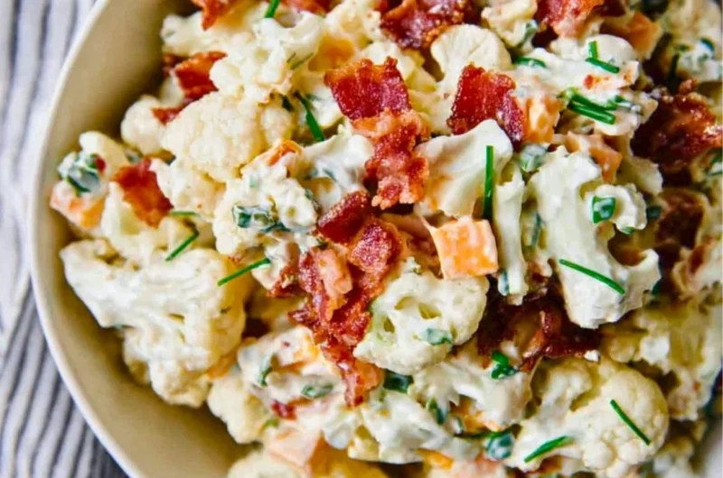 A colorful loaded cauliflower salad with fresh vegetables and toppings.