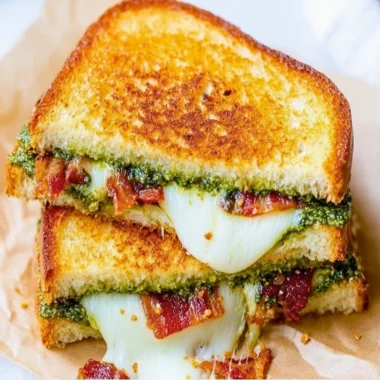 Pesto grilled cheese sandwich with melted cheese and fresh basil