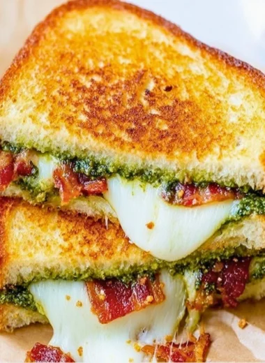 Pesto grilled cheese sandwich with melted cheese and fresh basil