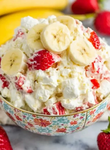 Bowl of strawberry banana fluff salad with whipped cream and fresh fruit