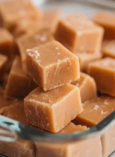 Delicious homemade peanut butter fudge in a square shape on a wooden board.