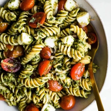 Delicious pesto pasta salad with cherry tomatoes, vegetables, and basil.