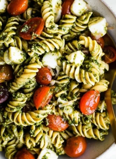 Delicious pesto pasta salad with cherry tomatoes, vegetables, and basil.